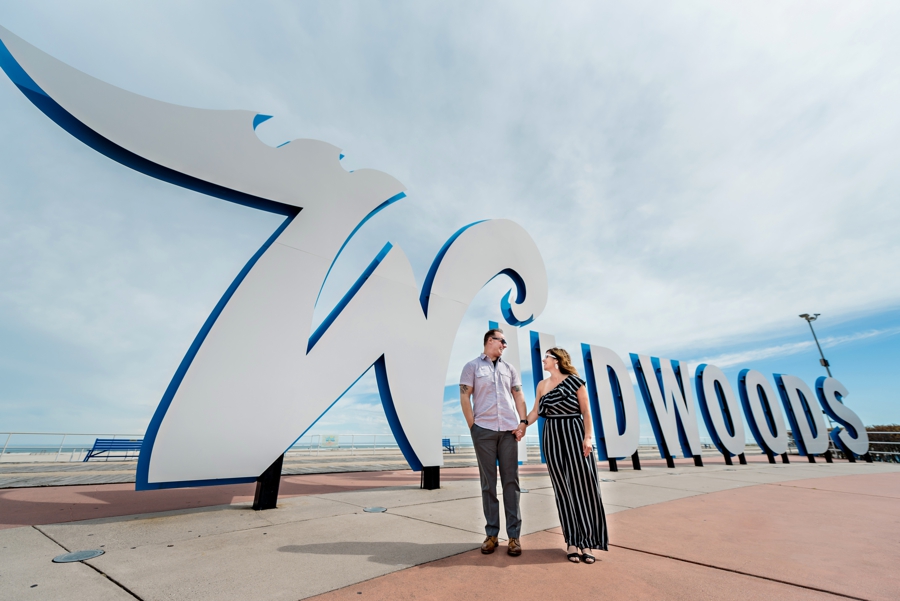 A man and woman in front of the Wildwood sign at the shore.